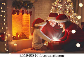 Merry Christmas! happy family mother father and child with magic gift near tree