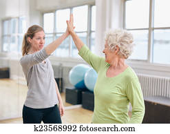 Senior woman rejoicing health success with her trainer at rehab