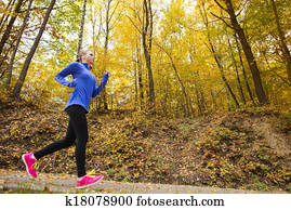 Active and sporty woman runner in autumn nature