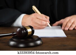 Judge Writing On Legal Documents At Desk Judge Writing On Legal Documents At Desk