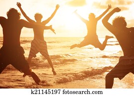 group of young people jumping at the beach 