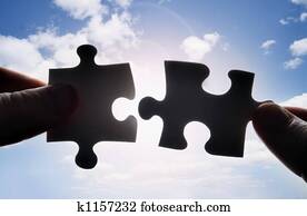 Hands trying to fit two puzzle pieces together Hands trying to fit two puzzle pieces together
