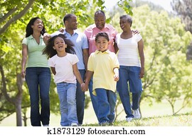 Extended family walking in park holding hands and smiling Extended family walking in park holding hands and smiling