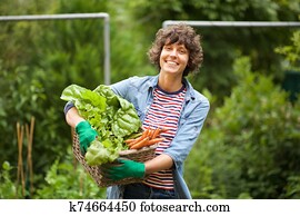 female farmer smiling with bunch of vegetables in basket female farmer smiling with bunch of vegetables in basket