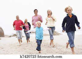 Three Generation Family Running Along Winter Beach Together