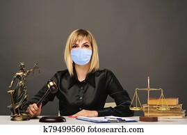 A young fair woman judge in protective mask works in her office. A young fair woman judge in protective mask works in her office.