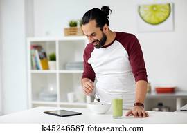 Homme avec tablet pc prenant son petit déjeuner à la maison Homme avec tablet pc prenant son petit déjeuner à la maison