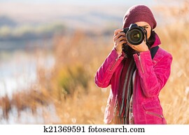 young woman photographing in autumn