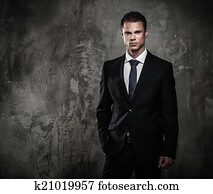 Well-dressed man in black suit against grunge wall 
