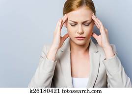 I have to concentrate. Depressed young businesswoman touching her cheekbone and keeping eyes closed while standing against grey background