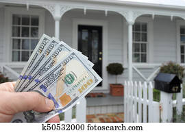 A mans hand holds US against a front of North American hous