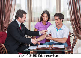 closeup on happy man taking keys to new house. agent giving keys to young couple purchasing new house and shaking hands