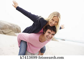 Man Giving Woman Piggyback On Winter Beach Man Giving Woman Piggyback On Winter Beach