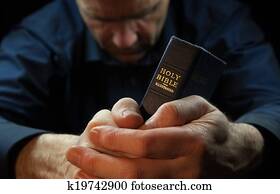 A Man praying holding a Holy Bible. A Man praying holding a Holy Bible.