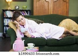A young woman lying on her couch eating cereal