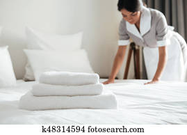 Young hotel maid setting up pillow on bed Young hotel maid setting up pillow on bed