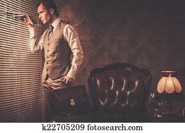 Well-dressed man with a briefcase looking through jalousie 