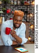 Delighted cheerful young man drinking his coffee