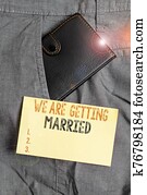 Writing note showing We Are Getting Married. Business photo showcasing Engagement Wedding preparation Loving couple Small wallet inside trouser front pocket near notation paper. Writing note showing We Are Getting Married. Business photo showcasing Engagement Wedding preparation Loving couple Small wallet inside trouser front pocket near notation paper.