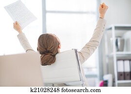 Happy business woman with document rejoicing at work. rear view