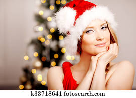 Young beautiful smiling santa woman near the Christmas tree. Fashionable luxury woman celebrating New Year. Beauty luxury trendy blonde.