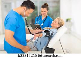 medical doctor taking mid age woman's blood pressure