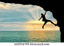 Mountaineer climbs cliff over sea sunset Mountaineer climbs cliff over sea sunset