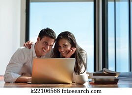 relaxed young couple working on laptop computer at home