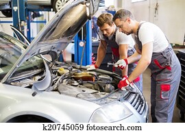 Two mechanics fixing car in a workshop Two mechanics fixing car in a workshop