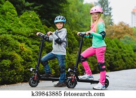 Happy kids standing on electric scooter outdoor