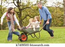 Parents Giving Children Ride In Wheelbarrow Parents Giving Children Ride In Wheelbarrow