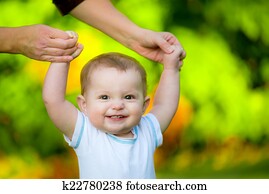 Smiling happy baby learning to walk outdoors