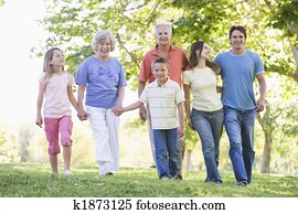 Extended family walking in park holding hands and smiling