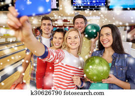 happy friends with smartphone in bowling club happy friends with smartphone in bowling club