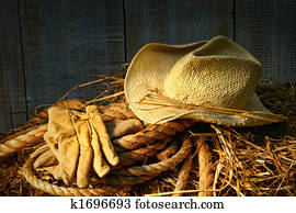 Straw hat with gloves on a bale of hay Straw hat with gloves on a bale of hay
