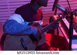 African american professional musician recording guitar in digital studio at home, music production technology concept, close-up.