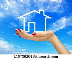 White house in woman hand over blue sky. Real estate