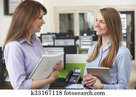 Two Businesswomen Having Discussion In Office