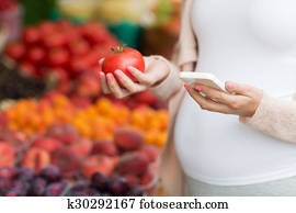 pregnant woman with smartphone at street market