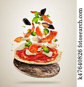 Flying sea food ingredients with pizza dough, on gray background Flying sea food ingredients with pizza dough, on gray background