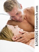 Couple lying in bed smiling