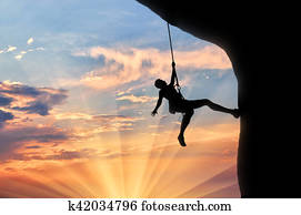 Mountaineer climbs cliff sunset Mountaineer climbs cliff sunset