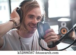 Cheerful male musician performing song in sound recording studio
