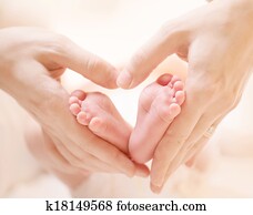 Tiny Newborn Baby's feet on female Heart Shaped hands closeup Tiny Newborn Baby's feet on female Heart Shaped hands closeup