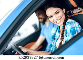 A woman is sitting at the wheel of a new car.