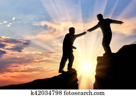 Man helps friend in mountains of giving helping hand sunset Man helps friend in mountains of giving helping hand sunset