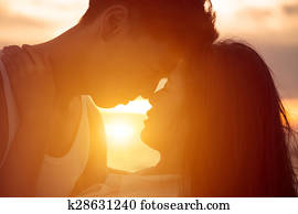 young couple kissing at sunset on beach