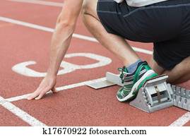 Mid section of a man ready to race on running track