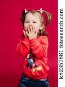 Smiling little girl in red sweatshirt hiding surpised face. Smiling little girl in red sweatshirt hiding surpised face.