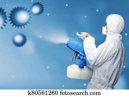 Man in a white protective suit spraying disinfectant in the air Man in a white protective suit spraying disinfectant in the air
